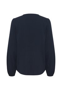 Námořnická modrá blůza s dlouhými elastickými rukávy a kulatým lemem. Hladká textura látky s mírným leskem, bez viditelných vzorů nebo kovových doplňků.