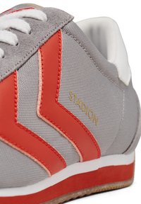 Hallid hallid tennisetooted punaste ja virsiku aktsentidega, sujuva tekstuuriga, valged paelad ja kuldne "STADION" logo küljes.