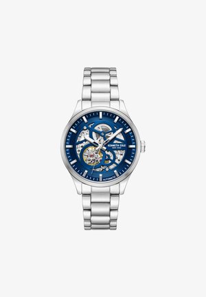 Automatické hodinky so strieborným nerezovým remienkom, modrým ciferníkom a priehľadným puzdrom, ktoré vystavuje zložitú súčiastkovú mechaniku.