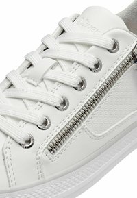 Baskets en cuir blanc avec des lacets ronds et des éléments en métal argenté. Les caractéristiques comprennent une fermeture éclair décorative sur le côté et des accents texturés sur le flanc.