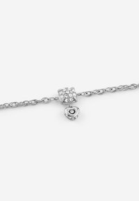Il braccialetto a catena d'argento presenta un ciondolo cubico decorato con cristalli trasparenti e un pendente a forma di cuore con una pietra centrale e dettagli intricati.