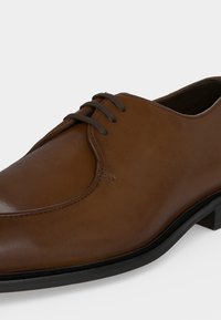 Καφέ δερμάτινο ανδρικό επίσημο παπούτσι με μαύρη σόλα και σκούρα καφέ κορδόνια, με λείο φινίρισμα και κλασικό σχέδιο οξφόρδης.