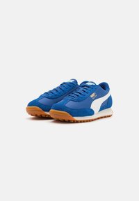 Zapatillas de ante azul y sintéticas con un logo de PUMA blanco, suela de goma y banda de rodadura texturizada. Presenta un diseño con cordones y un collar acolchado.