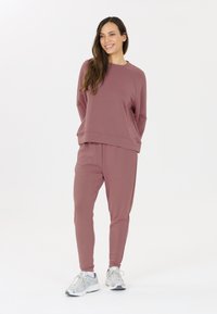 Roze sweatshirt en bijpassende broek gemaakt van zachte stof, met een relaxte pasvorm, geribde manchetten en een eenvoudig ontwerp.