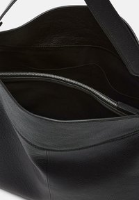 Czarna skórzana torba tote o teksturowanym wykończeniu. Posiada przestronną kieszeń wewnętrzną, kieszeń na zamek oraz gładką podszewkę.