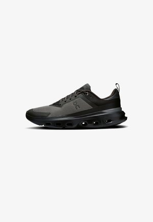 Zapatillas de correr negras con una parte superior de malla, detalles texturizados y una suela negra acolchada con orificios de aire para transpirabilidad y flexibilidad.