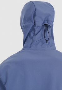 Personne portant une veste à capuche bleu clair, vue de dos, avec un cordon de serrage noir réglable sur la capuche.