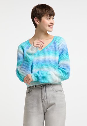 Maglione all'uncinetto in diverse tonalità di blu e bianco, scollatura a V, texture a coste, maniche lunghe, abbinato a jeans grigio chiaro.