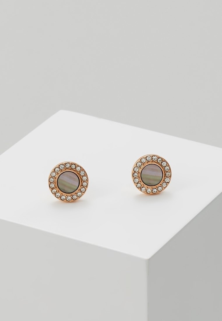 Boucles d'oreilles rondes en or avec des centres irisées foncés, chacun entouré d'un anneau de petites pierres claires et scintillantes, exposées sur une plateforme blanche.