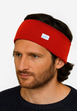 Red ribbed headband made of soft knit material with a white tag detail. Designed to fit comfortably around the head.