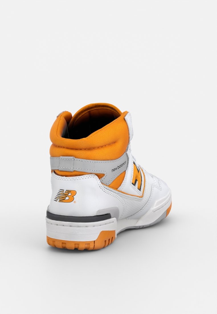 Baskets montantes blanches avec des accents oranges, dotées d'un col rembourré, d'une sangle ajustable et de matériaux en cuir texturé et synthétique.