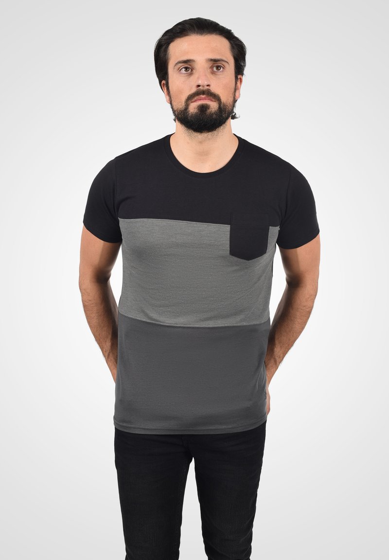 Černé a šedé tričko s krátkým rukávem, které má horizontální design barevných bloků a kapsu na hrudi. Měkká, hladká textura a slim fit.