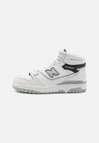 Mid-top athletic shoe in white leather and grey suede, featuring a perforated design, black accents, and a grey rubber outsole.