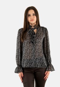 Blusa negra con estampado, hecha de tejido transparente, que presenta un detalle de cuello atado, mangas largas con puños fruncidos y cierre de botones en la parte delantera.