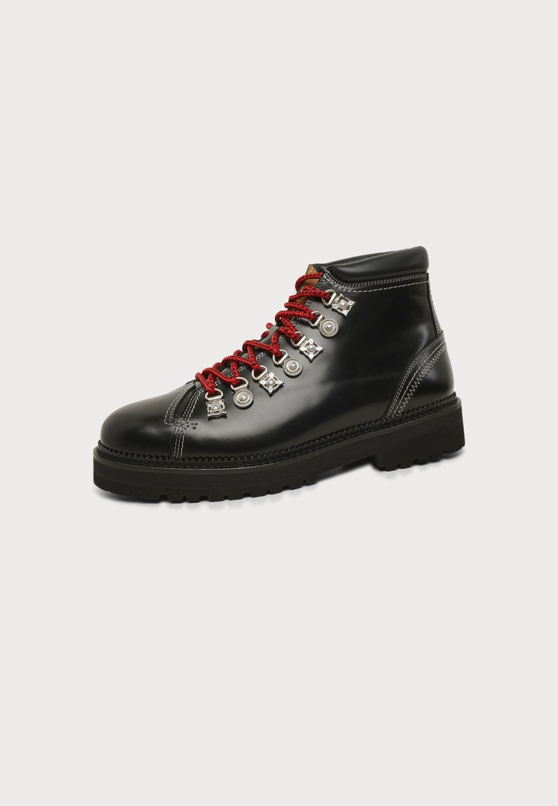 Botte de randonnée en cuir noir avec lacets rouges, œillets métalliques, semelle noire épaisse et couture blanche détaillée sur un fond clair uni.