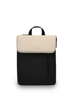 Sac à dos bicolore avec rabat beige, corps noir, poignée supérieure, et poche zippée verticale à l'avant, posé debout sur un fond blanc.