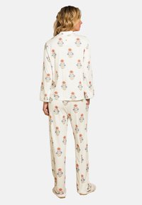 Floral-patterned cream pajama set featuring a long-sleeve top and loose-fitting pants. Made of soft fabric with autumn-colored flowers.