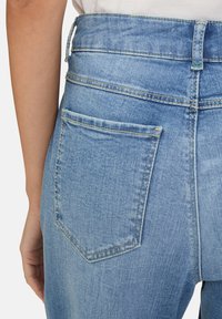 Jeans in denim azzurro chiaro con vita alta, dotati di una tasca posteriore con dettagli di cucitura e tessuto testurizzato.