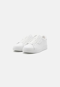 Hvite sneakers med glatt skinnoverdel, rund tå, snøring og teksturert gummisåle. Rent design med minimal merkevare.
