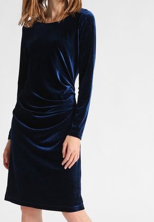 Langärmeliges, knielanges Kleid aus tiefseeblauem Samt. Mit rundem Ausschnitt, drapierten Details an der Taille und glatter Textur.