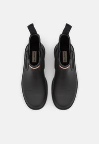 Black rubber ankle boots with elastic side panels, featuring a flat sole and a red and white striped accent at the heel.