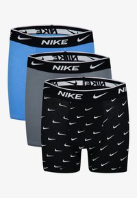 Trīs Nike bokseršortu pāri: viens zilā, viens pelēkā, viens melnā ar baltām Nike logo. Katrai ir melna josta ar logo tekstu.