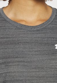 Grå atletisk skjorte med et struktureret mønster, der har en rund halsudskæring og en lille hvid logo på siden.