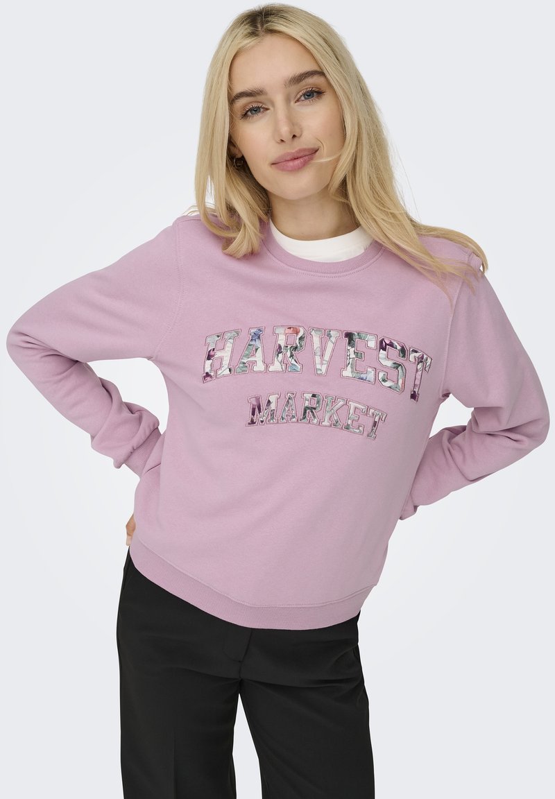 Lichtroze sweater gemaakt van zacht materiaal met gestructureerde "HARVEST MARKET" letters in kleurrijke bloemenprint. Ontspannen pasvorm, ronde hals.