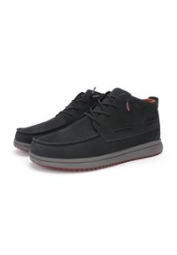 Scarpe nere in suede con un design a basso profilo, suola in gomma grigia e accenti rossi a contrasto. Presentano lacci e dettagli cuciti sulla parte superiore.