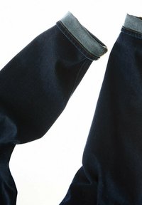 Mörkblå denimjeans med en ljusblå denimupprullning. Tyget är slätt med lätt blekning, har kontrasterande sömmar och en avslappnad passform.