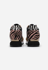 Zapatillas con print animal que presentan una mezcla de piel sintética negra y rosa, con rayas audaces, una suela negra y detalles metálicos en el talón.