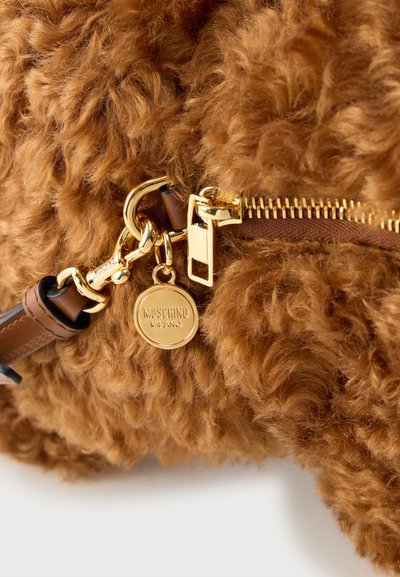 Καφέ υφή υφάσματος με καφέ καφέ υφής και χρυσό φερμουάρ και δίπλωμα με στρογγυλή χρυσή ετικέτα Moschino Milano σε δερμάτινο λουρί.