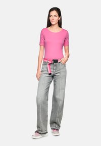 Fitted pink short-sleeve top paired with high-waisted, wide-leg gray jeans featuring white stitching, a pink belt, and pink sneakers.