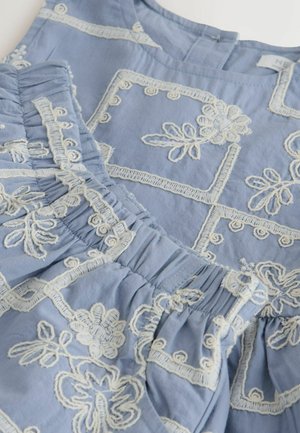 Vaaleansininen kangas, jossa valkoisia kirjottuja kukka- ja geometrisia kuvioita, poimutettuja osia ja pyöreä pääntie.