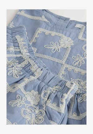 Helehall värvusega kangas, mis on kaunistatud valgete tikitud loövliste ja geometriliste motiividega, kogutud osade ning ümar kaelusega.