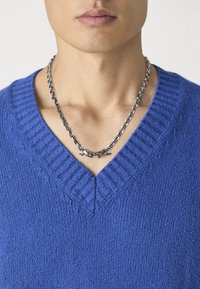 Blue textured v-neck sweater with ribbed neckline, paired with a silver chain necklace featuring a detailed design at the center.