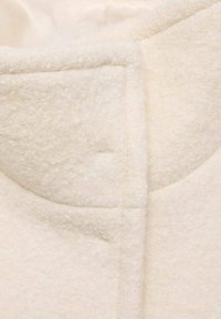 Crème-kleurige fleece stof, met een gestructureerd oppervlak, zichtbare stikdetails en een gestructureerd kraagontwerp.