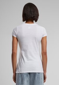 Witte aansluitende t-shirt met korte mouwen en een ronde hals, gemaakt van zachte katoen, met een gladde textuur en een minimaal ontwerp.