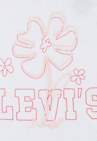 Hvid bomulds t-shirt med rød syning af ordet "LEVI'S" og et blomstermotiv i pink kontur med små blomsterdetaljer.