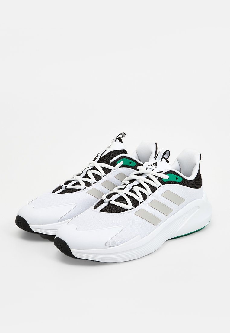 Chaussures de sport blanches avec des accents noirs et gris, tige en mesh texturé, lacets blancs et détail vert près du talon. Semelle extérieure en caoutchouc.