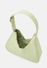 Vihreä käsilaukku krokotiilin tekstuurilla, leveällä hihnalla ja kultaisilla vetoketjuterroksilla. Avoin muotoilu paljastaa yksivärisen sisuksen.