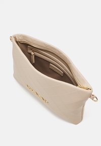 Pochette matelassée beige Valentino avec fermeture éclair et logo dorés, ouverte pour montrer une poche intérieure zippée et une doublure lisse.