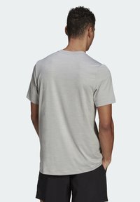 Ljusgrå kortärmad skjorta med en slät yta och rundad halsringning, med ett subtilt melerat mönster på baksidan.