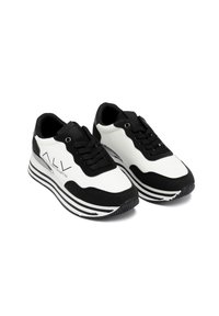 Zwart-witte sneakers met een strak ontwerp, zachte materialen, textuuraccenten in het zwart en gedurfde streepdetails op de zool.