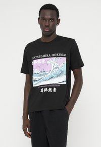 Μαύρο T-shirt με γραφικό κύματος του Κατσούσικα Χοκουσάι σε μπλε και ροζ χρώματα, με αντίθετο λευκό κείμενο και σχέδιο άνετης εφαρμογής.