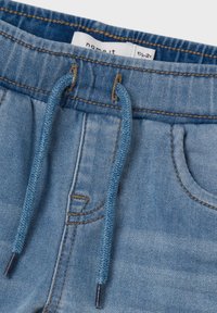 Denim shorts med elastisk midje og snor. Lys blå farge, sømdetaljer og frontlommer. Glatt stoffstruktur.