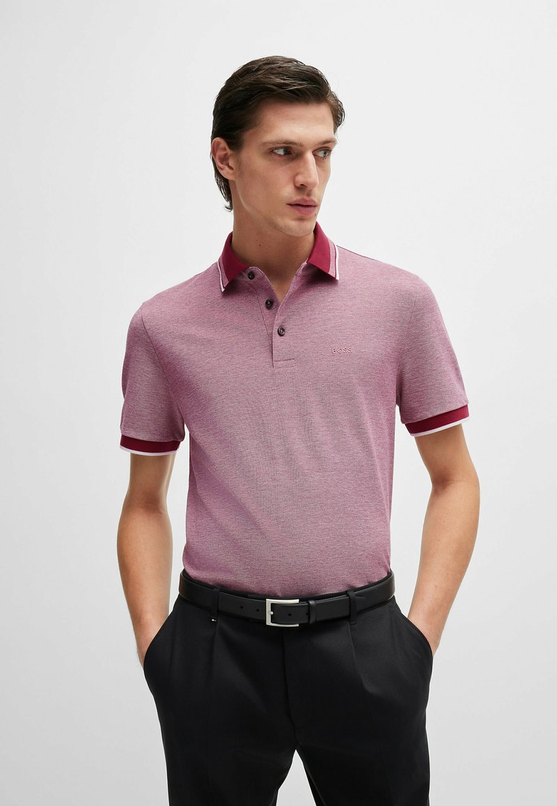 Polo shirt in lichtrood met een gestructureerde weving, contrasterende donkerrode kraag en manchetten, een drukknoopsluiting met drie knopen en een geborduurd logo op de borst.