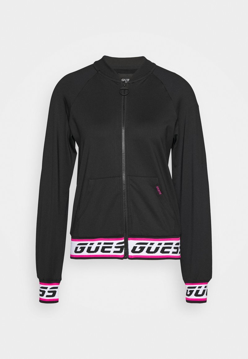Veste noire zippée avec col et poignets côtelés, poches avant, bandes blanches et roses aux poignets et à l'ourlet avec le logo "GUESS".