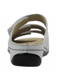 White leather sandal with cut-out straps, a padded interior, black rubber sole, and contrasting stitching along the edges.