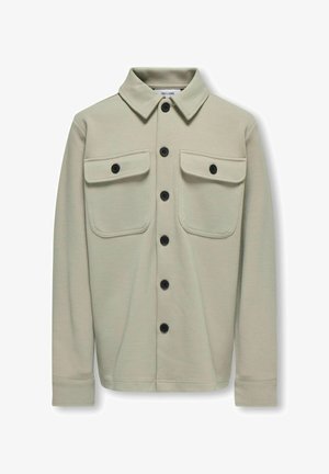 Svetlo bež dolgi rokavi srajca-jacket iz teksturirane tkanine, s poudarjenim ovratnikom, dvema žepoma na prsih in črnimi gumbi.